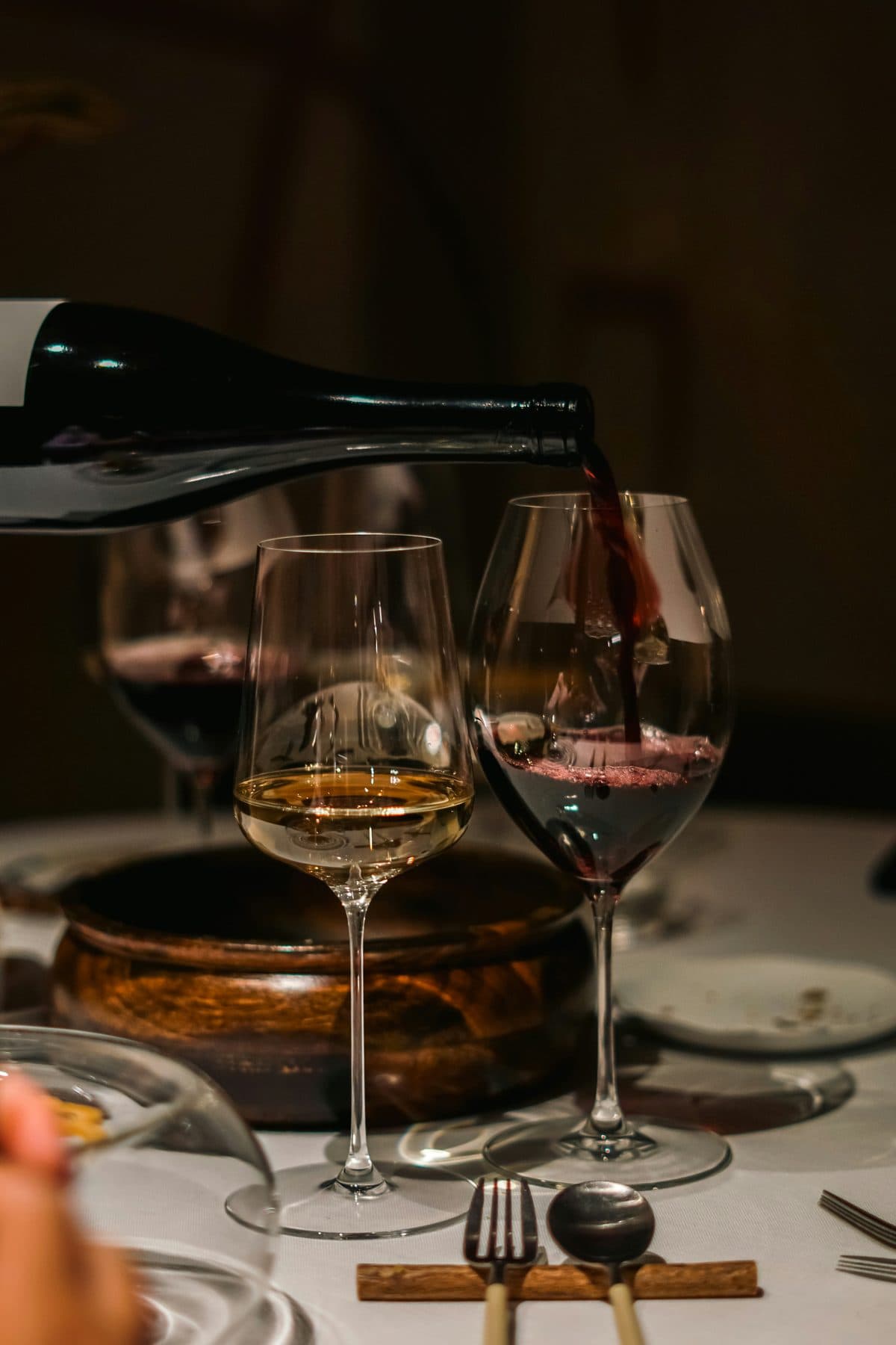 Diner bij kaarslicht, twee glazen wijn worden ingeschonken
